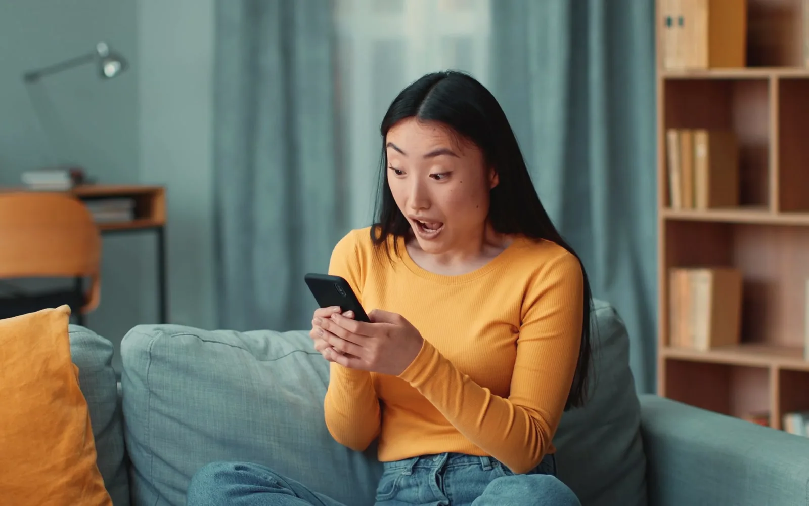 An artist reacting with delight to a booking message on her phone