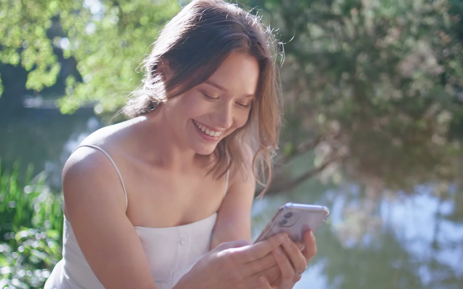 A woman smiling at her phone in warm afternoon light
