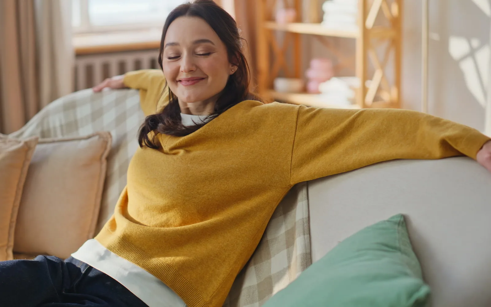 A woman resting on a sofa in warm afternoon light, smiling softly